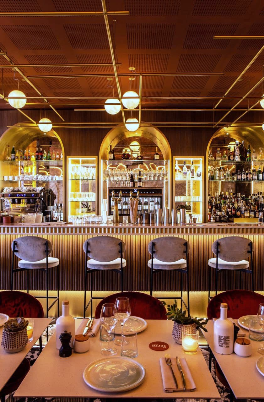 Le bar et ses trois arcades rétroéclairées, tabourets alignés et plafond de laiton perforé