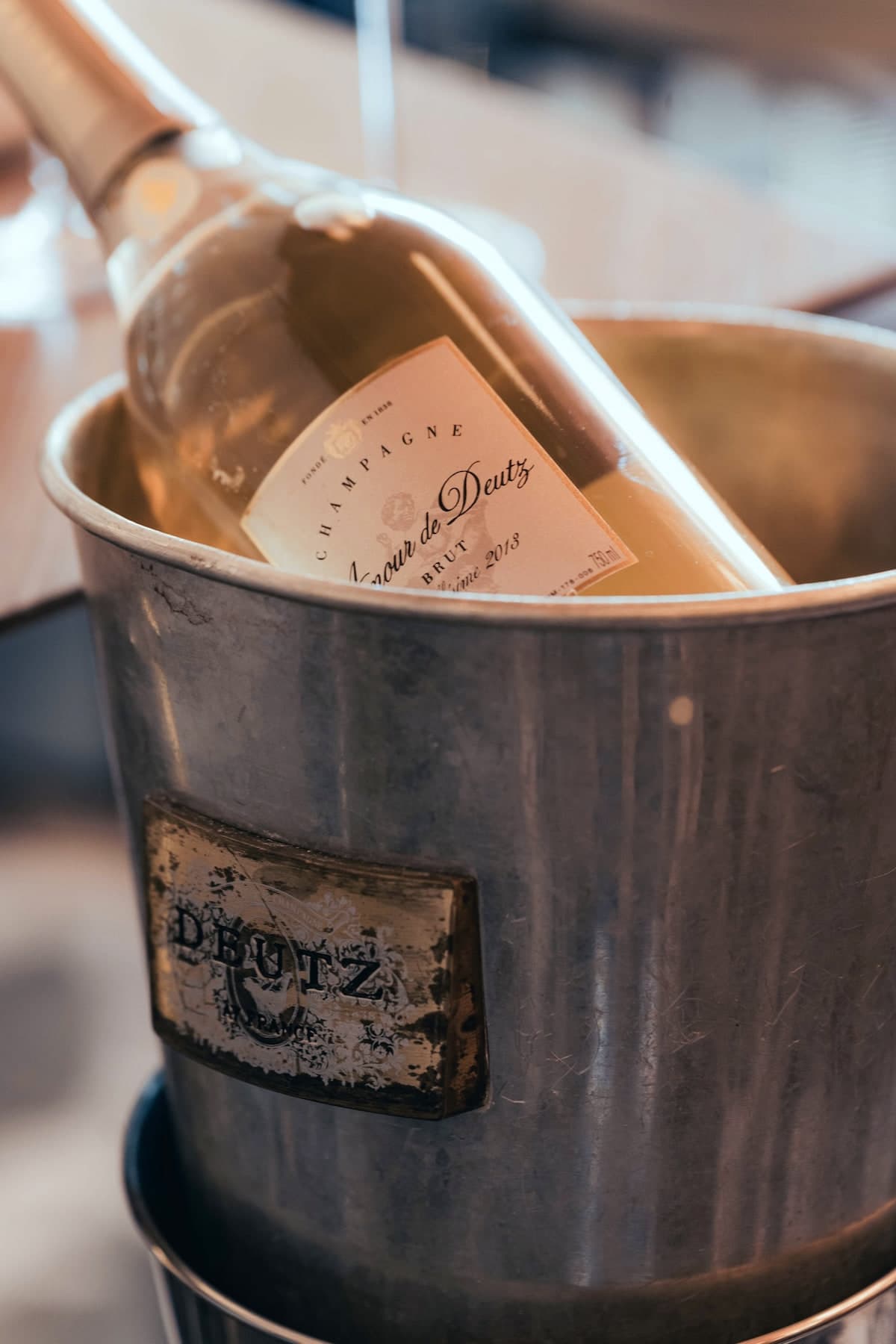 Bouteille de champagne rosé couchée dans un seau de métal patiné gravé Deutz